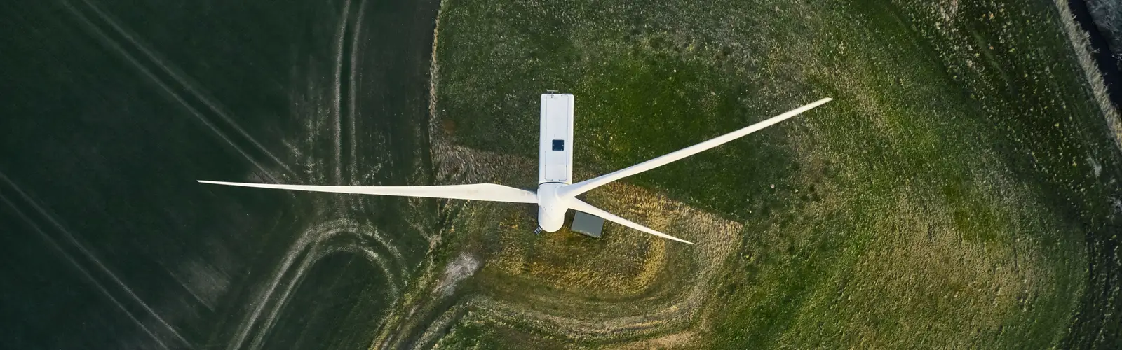 Aerial view of a wind turbine surrounded by green natural landscape, showcasing the integration of renewable energy into the environment. Aerial view of a wind turbine surrounded by green natural landscape, showcasing the integration of renewable energy into the environment.