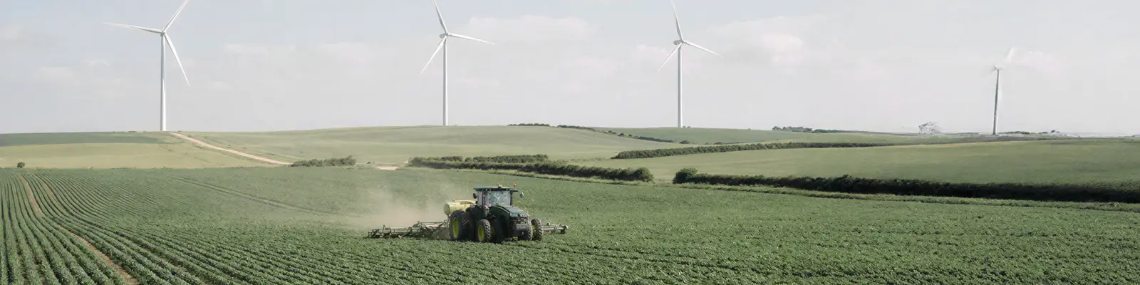 Tractor working on a green field with wind turbines in the background. Tractor working on a green field with wind turbines in the background.